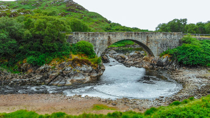 Fototapeta na wymiar Ancient stone bridge in the Highlands of Scotland - typical scenery