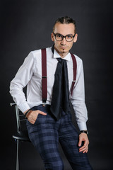 Fototapeta premium Young handsome boy in white shirt with tie sitting on the chair