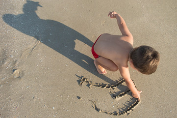 the child paints on the wet sand. the wave receded. the kid draws lines.