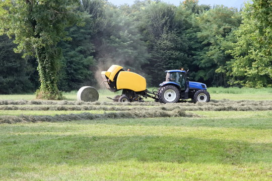 trattore agricolo blu con macchina fienagione 