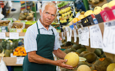 Seller putting products on shelves in greengrocery