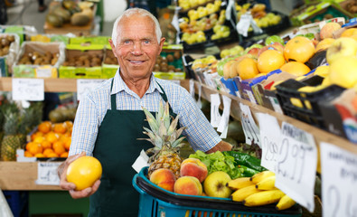 Elderly salesman working in greengrocery