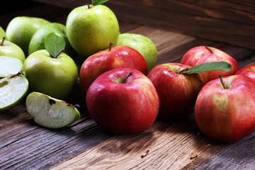 Ripe red apples with leaves on wooden background.