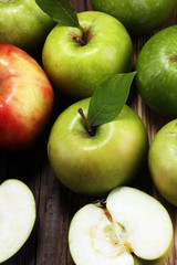 Ripe red apples with leaves on wooden background.