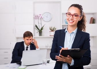 charming young woman manager holding cardboard in office
