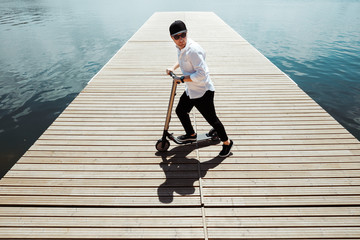 Photo of modern man with electric scooter at a wooden pier