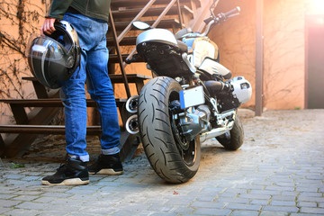 Naklejka premium Moto biker in helmet arrives to home. Motorcycle and motorcyclist safety background.
