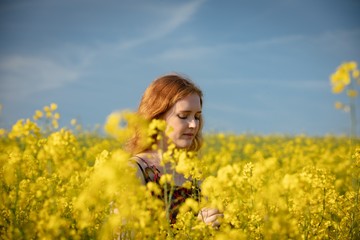 Woman touching crops in the mustard field on a sunny day