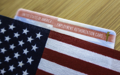 Employment autorization card of United States of America covered  American Flag. Wooden surface. Diagonal view perspective.