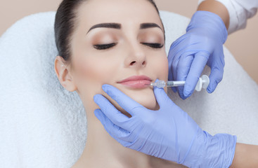 Obraz na płótnie Canvas The doctor cosmetologist makes Lip augmentation procedure of a beautiful woman in a beauty salon.Cosmetology skin care.