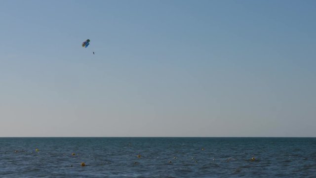 Tourist parasailing with parachute over the sea with blue sky