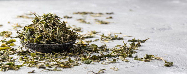 Loose dried white tea leaves on grey background 