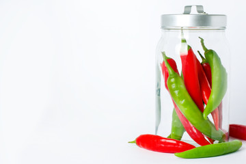 Colorful peppers in glass jar on white background. Vegan food concept