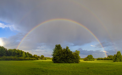 Naklejka premium Rainbow after a thunderstorm over a road