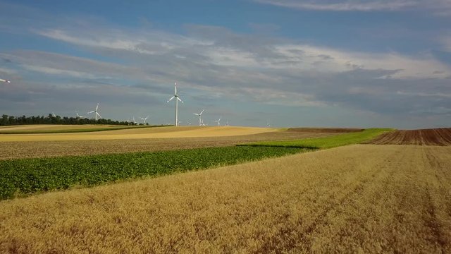 Drone flight over wheat fields in Austria with wind turbines