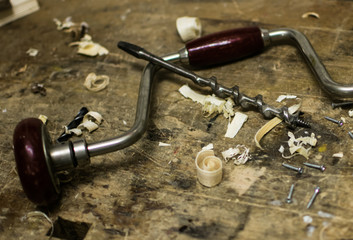 Old vintage hand drill with old drill bit and wood shavings in wood workshop for binder