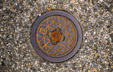 Old rusty sewer cover on street out of heavy metal