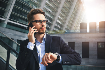 Business man stand at street holding a smartphone in office park