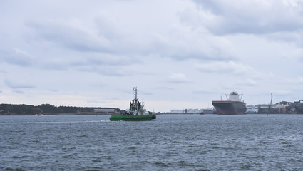 Green ship on the water. Accompanying ship.