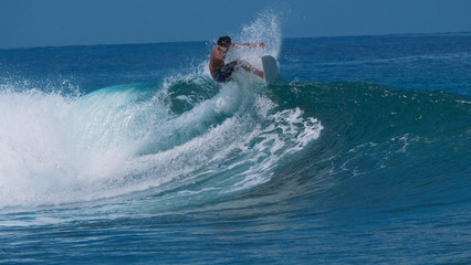 CLOSE UP: Beautiful emerald tube wave curls behind extreme male rider surfing.