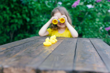 cute little girl playing with rubber duck and plastic binoculars outdoors. beautiful baby having fun with a toy duckling. home development of children. what are the interests of modern children?