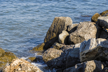 Fototapeta na wymiar Sea waves are fighting against the big rocks on the shore.