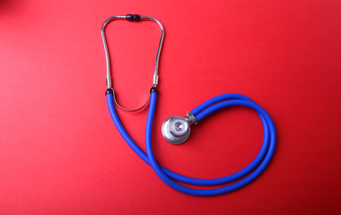 Medical blue stethoscope isolated on red background