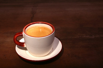 A cup of espresso coffee on a dark wooden background