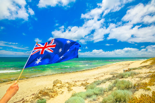 Australian flag waving on the foreground with coastal landscape of Mettams Pool, Trigg Beach, North Beach near Perth in Western Australia. Tourism in Australia.