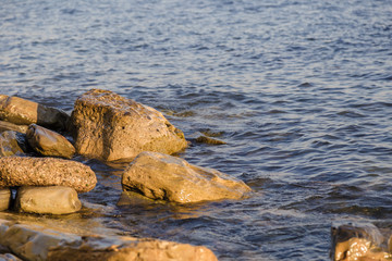 Sea waves are fighting against the big rocks on the shore.