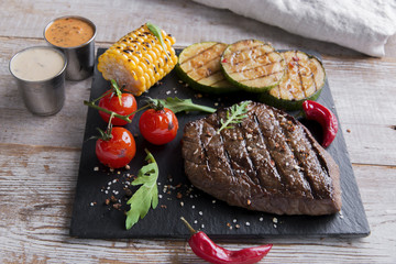 beef steak with grilled vegetables on a stone surface
