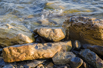 Sea waves are fighting against the big rocks on the shore.