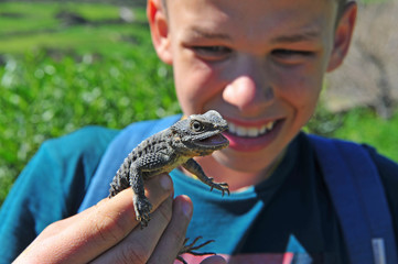 Young happy zoologist holding lizard in hands