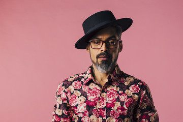 Simple portrait of mature man with beard and tilted hat, isolated on pink