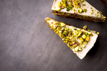 Raw vegan pistachio carrot cake with cashew cream layers from above on concrete table. Dark food photography styling concept.