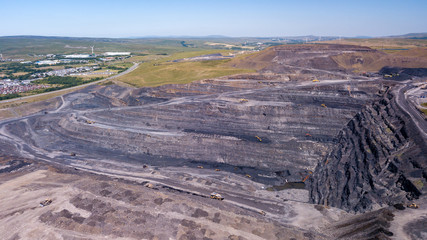 Aerial drone view of a huge opencast coal mine cut into a rural hilly area