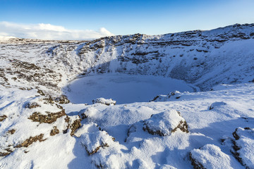 Panoramic view of the Kerid Volcano  Iceland with snow and ice in the volcanic crater lake in Winter under a blue sky