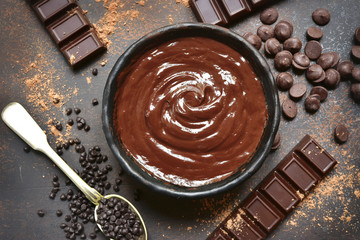 Chocolate ganache in a black bowl with ingredients for making.Top view.