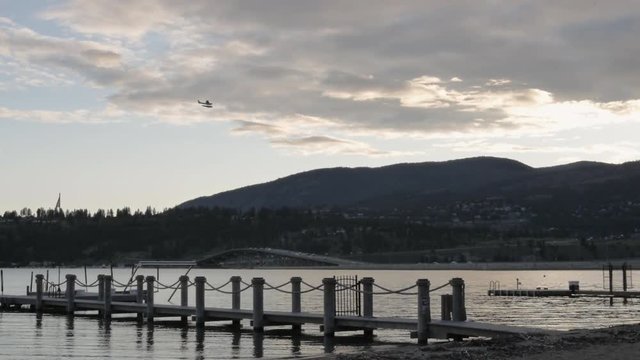 Slow Motion Sea Plane Flying Over Lake and Mountains at Sunset