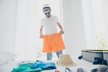 Young man trying on orange shorts before going to go on a long-awaited vacation