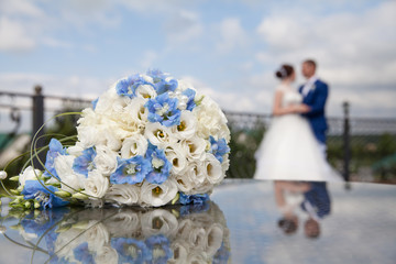 bouquet of white and blue flowers and the couple