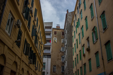 narrow backstreet urban city view scene of slums poor dirty old common buildings facade from below in gray rainy evening day