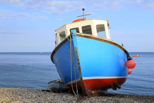 Blue fishing boat on the pebble beach near village of Beer in Devon