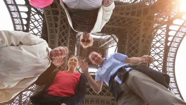 Professional video of happy family having fun and sending greetings under the Eiffel tower in Paris in 4k slow motion 60fps