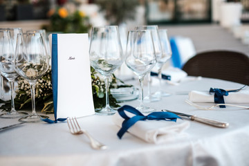 Tavola elegante di ristorante imbandita con menù, tovaglioli e posate per matrimonio e laurea