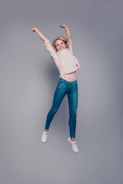 Full body length size vertical of attractive beautiful curly-haired blonde caucasian young girl wearing casual flying in air. Isolated over grey background