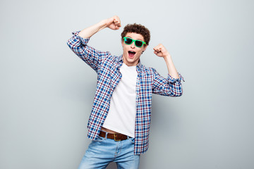 Portrait of happy brunet man with curly hair wearing in casual clothes and summer glasses, celebrate begining of holiday isolated on light gray background