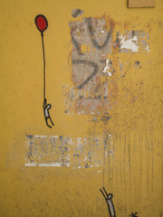 graffiti art on wall of man drawn up by balloon and another man reaching for him