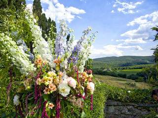Obraz premium Wedding bouquet against Tuscan landscape under blue clouded sky in Italy