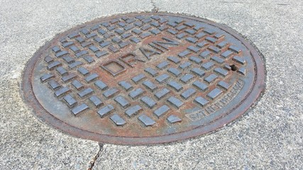 Drain metal cap on the floor/ road on bright day